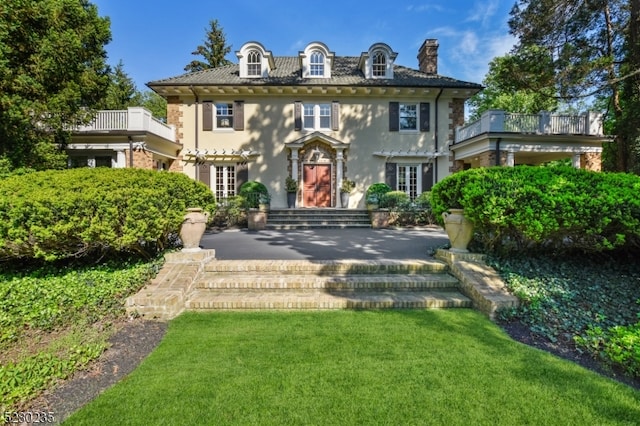 colonial home featuring a balcony and a front yard