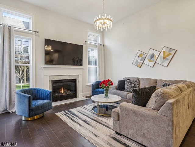 living room with a chandelier, dark wood-type flooring, and a fireplace