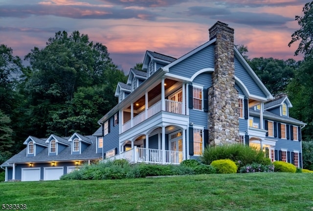 view of front of home with a garage, a balcony, and a lawn