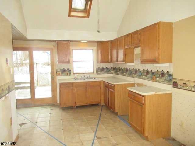 kitchen featuring light countertops, a skylight, a sink, and brown cabinets