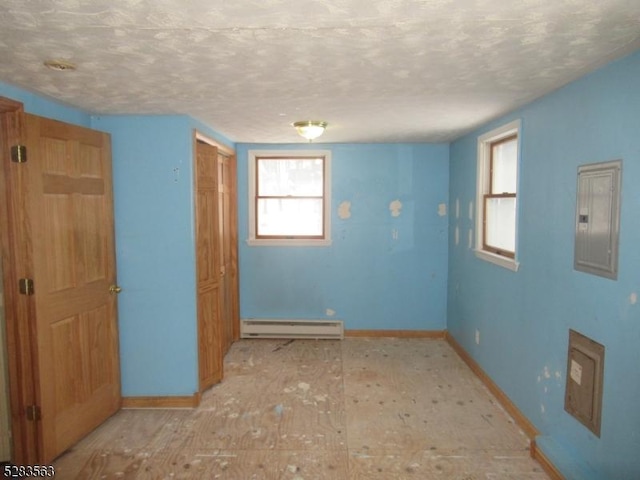 spare room featuring a baseboard heating unit, electric panel, and baseboards