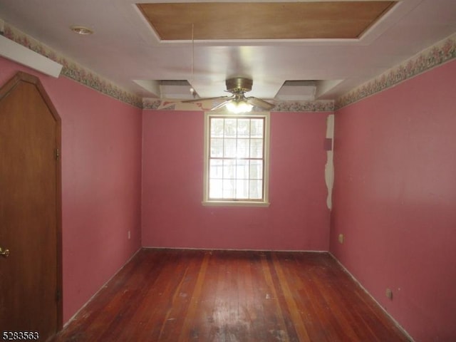 empty room with hardwood / wood-style flooring, attic access, and a tray ceiling