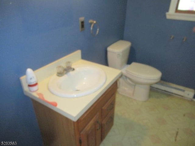 half bathroom featuring a baseboard heating unit, toilet, and vanity