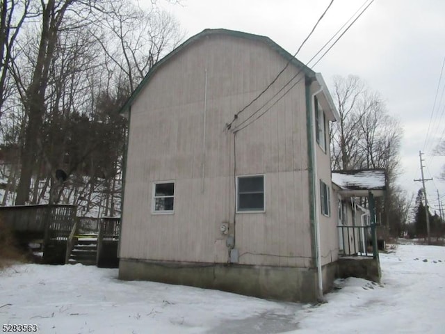 view of snow covered exterior featuring a garage and a wooden deck