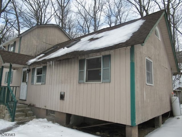 view of snow covered exterior featuring roof with shingles