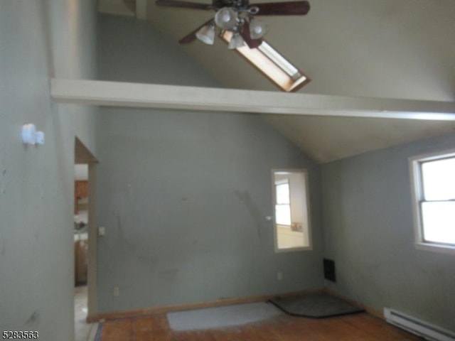 empty room with a baseboard heating unit, ceiling fan, vaulted ceiling, and wood finished floors