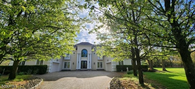 view of front of house with a front yard, decorative driveway, and stucco siding