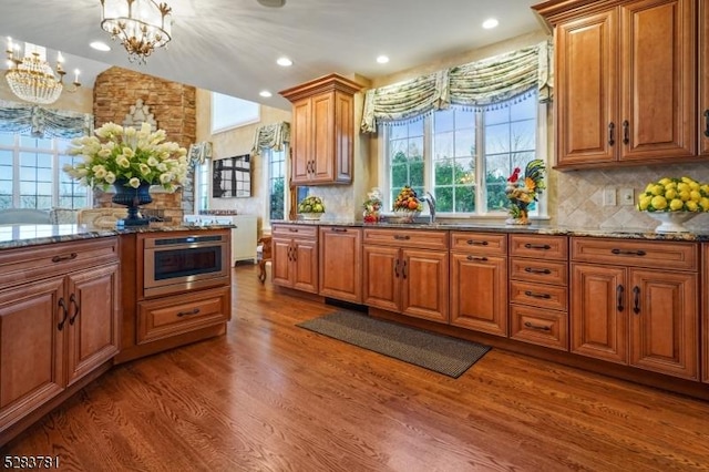 kitchen with dark stone counters, brown cabinets, and wood finished floors