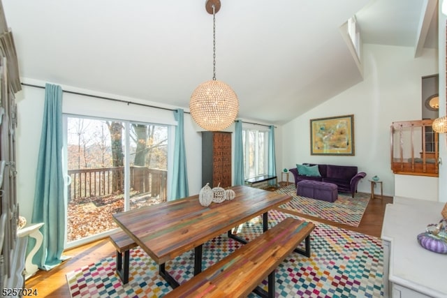 dining room with light wood-type flooring, lofted ceiling, and an inviting chandelier