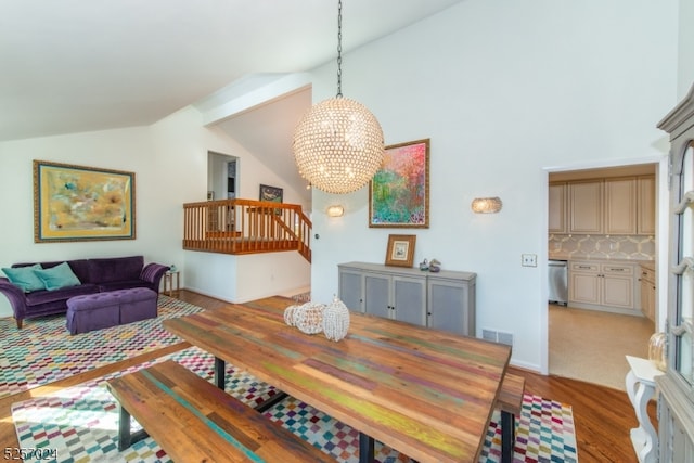 dining area with hardwood / wood-style floors, a chandelier, and lofted ceiling