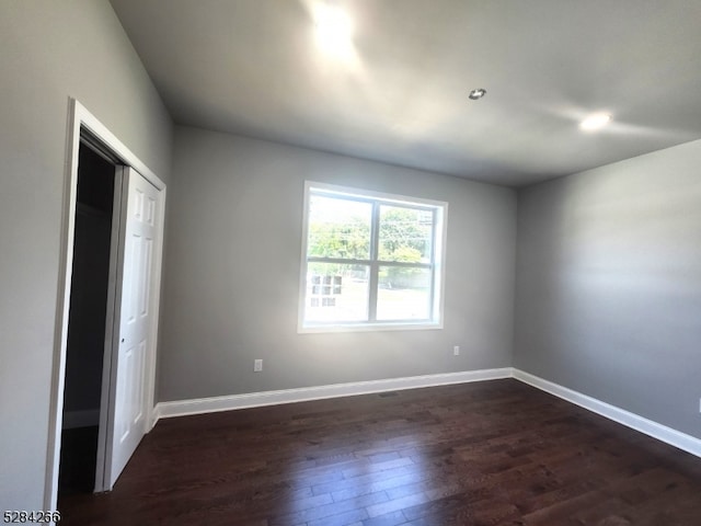 unfurnished bedroom with dark wood-type flooring and a closet