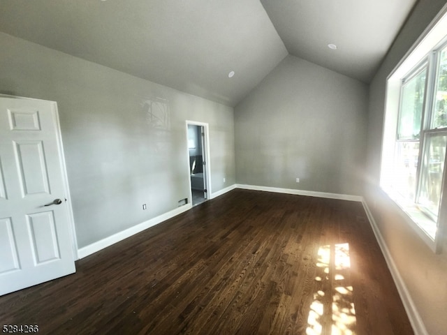 spare room featuring dark hardwood / wood-style floors and vaulted ceiling