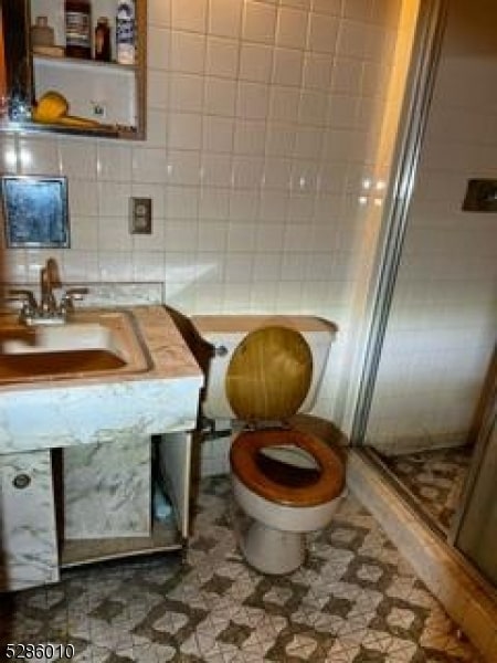 bathroom with toilet, tile walls, tasteful backsplash, and tile floors