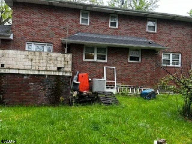 rear view of property featuring central AC and a lawn