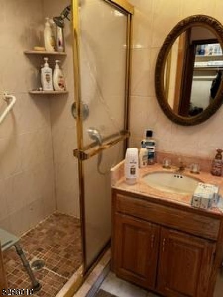 bathroom with a shower with door and vanity with extensive cabinet space