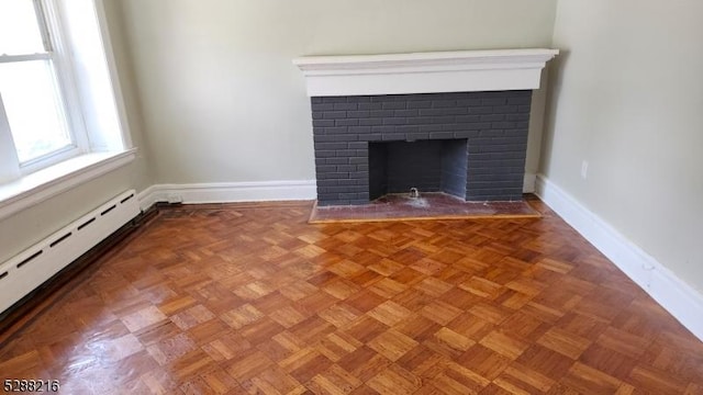 room details featuring a fireplace, a baseboard heating unit, and parquet flooring