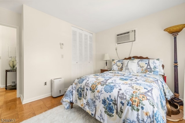 bedroom featuring a wall unit AC, a closet, and parquet flooring