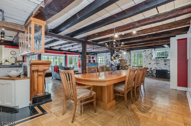 dining room featuring beamed ceiling, a healthy amount of sunlight, an inviting chandelier, and light parquet floors