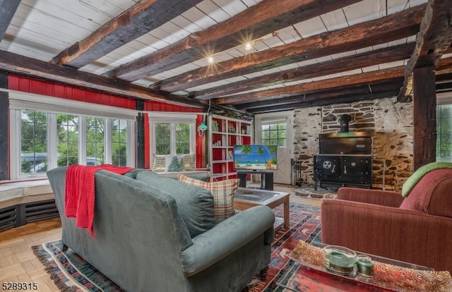 living room with beam ceiling, a wood stove, and parquet floors