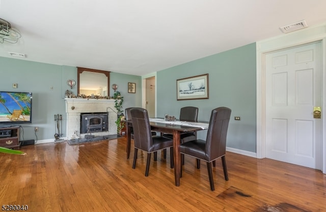 dining area with wood-type flooring and a wood stove