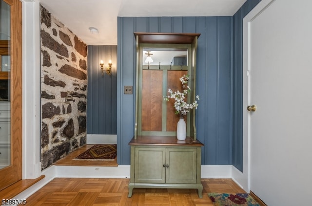 mudroom featuring wooden walls and light parquet flooring