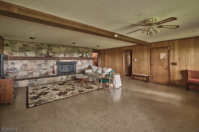 living room featuring beamed ceiling, a textured ceiling, ceiling fan, and a fireplace