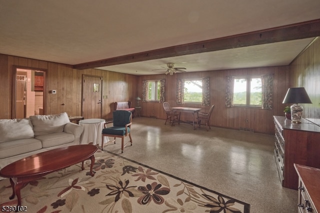 living room with beamed ceiling, ceiling fan, and wood walls