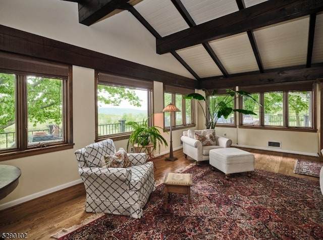 living room featuring a wealth of natural light, vaulted ceiling with beams, and hardwood / wood-style floors