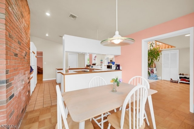 dining area featuring light parquet floors and brick wall