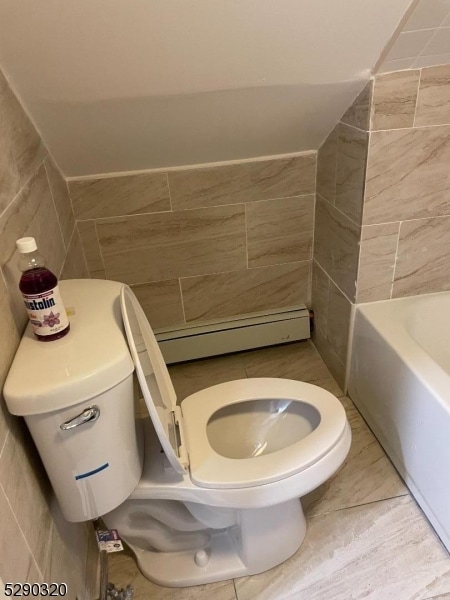 bathroom with a baseboard heating unit, tile flooring, tile walls, and toilet