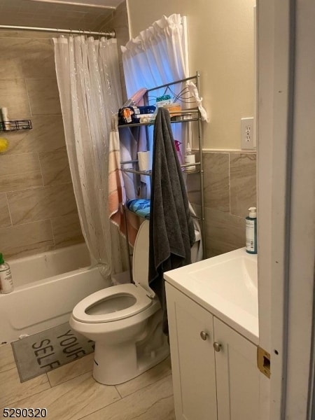 full bathroom featuring shower / bathtub combination with curtain, tile walls, toilet, and vanity