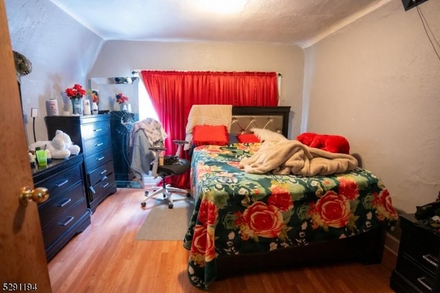 bedroom with vaulted ceiling and hardwood / wood-style flooring