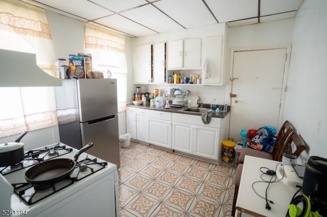 kitchen with white cabinets, decorative backsplash, white gas range, and a wealth of natural light