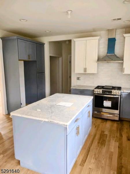 kitchen featuring backsplash, a high end fireplace, white cabinets, and light hardwood / wood-style floors