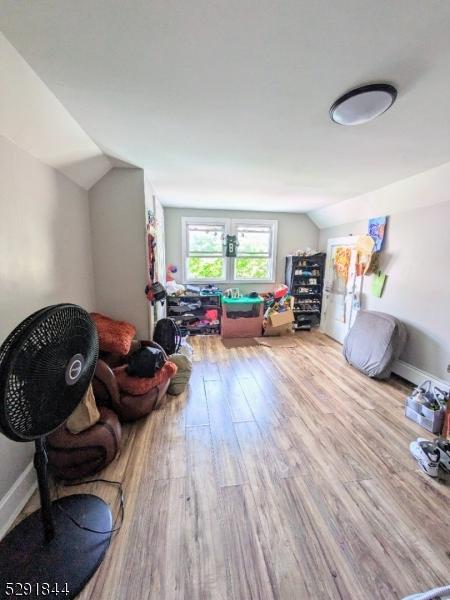 additional living space with light hardwood / wood-style floors and lofted ceiling