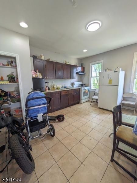 kitchen with dark brown cabinets, white appliances, and light tile patterned floors