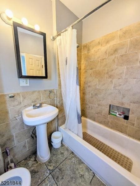 bathroom featuring shower / bath combo with shower curtain and tile walls