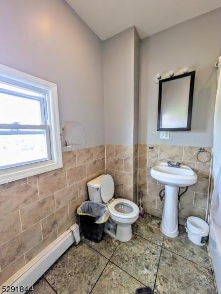 bathroom featuring tile patterned flooring, a baseboard radiator, toilet, and tile walls