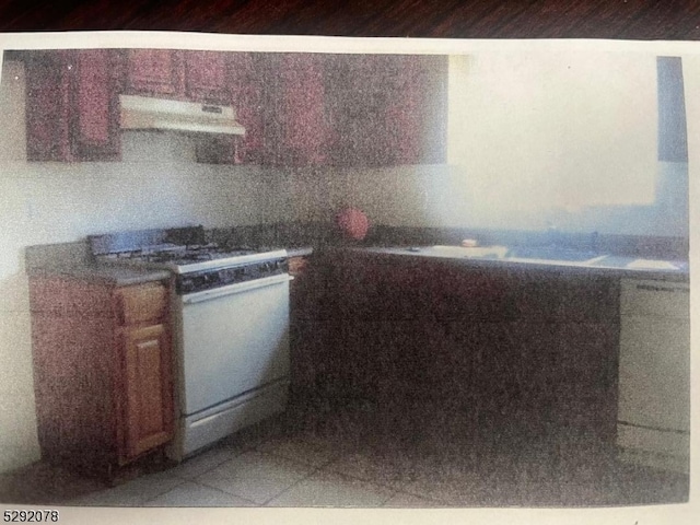 kitchen with exhaust hood, white stove, and tile patterned flooring