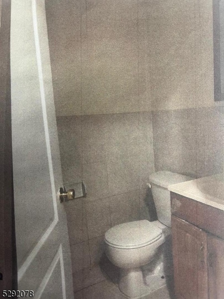 bathroom featuring toilet, vanity, and tile walls