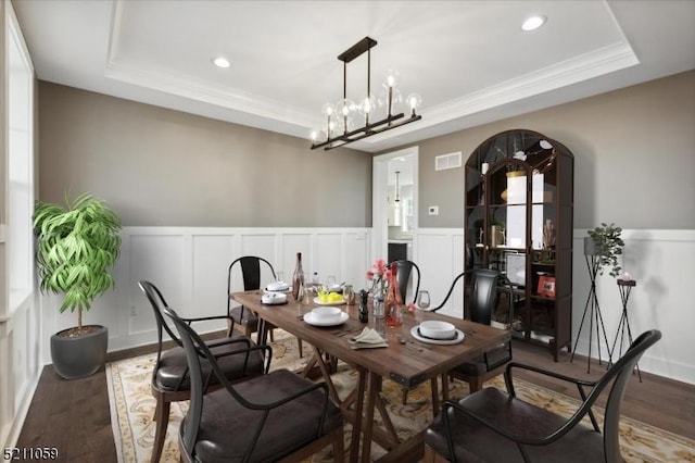 dining space featuring crown molding, an inviting chandelier, a tray ceiling, and hardwood / wood-style floors