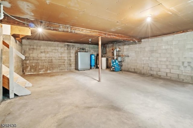 basement with water heater and fridge