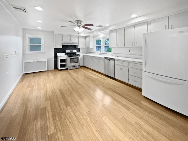 kitchen featuring backsplash, sink, light hardwood / wood-style flooring, ceiling fan, and stainless steel appliances