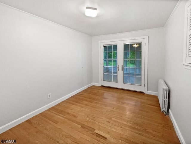 unfurnished room featuring radiator heating unit, hardwood / wood-style floors, and french doors