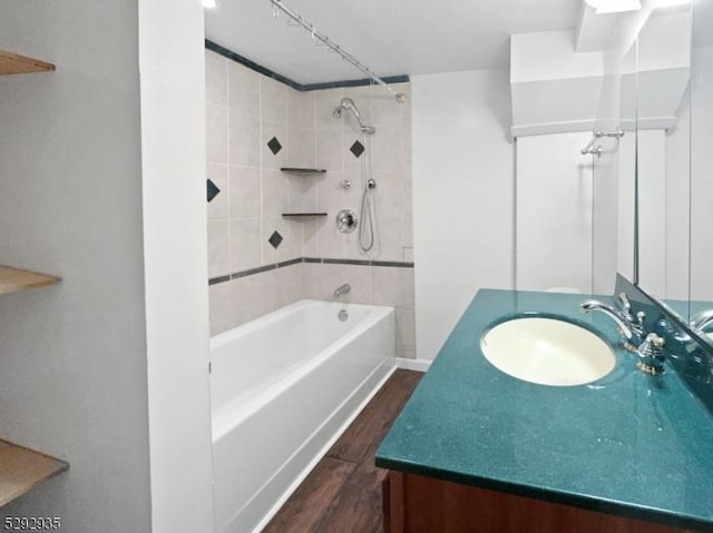 bathroom featuring hardwood / wood-style flooring, tiled shower / bath combo, and vanity