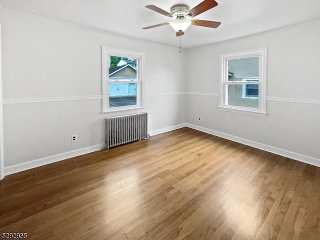 spare room featuring radiator, ceiling fan, and hardwood / wood-style flooring