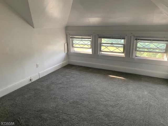 carpeted empty room with lofted ceiling