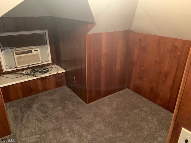 additional living space with lofted ceiling, cooling unit, carpet floors, and wooden walls