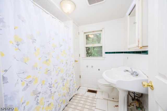 bathroom with tile walls, tile patterned floors, toilet, and walk in shower