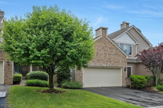 view of front of house featuring brick siding, a chimney, an attached garage, driveway, and a front lawn